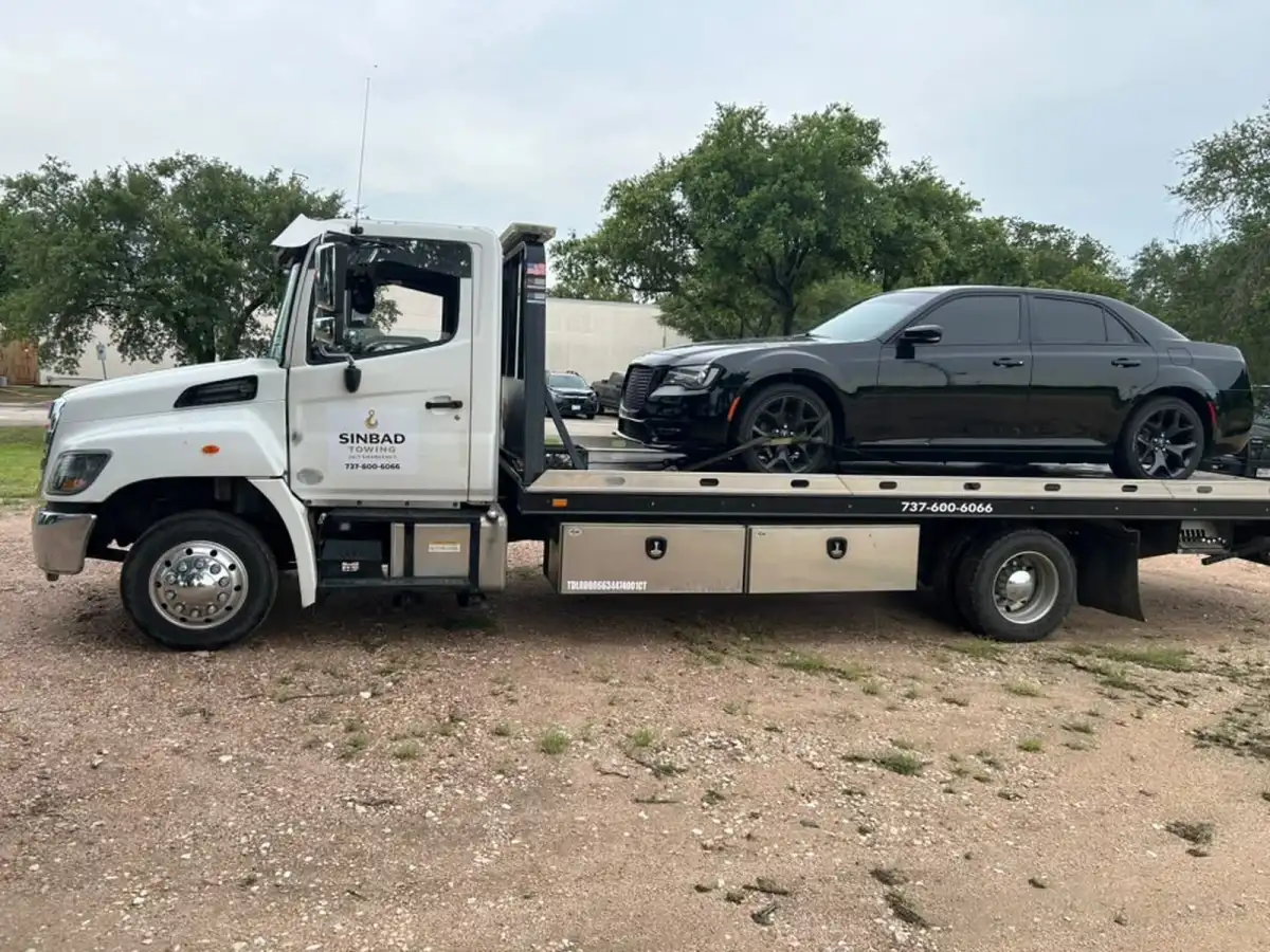 Sinbad Towing flatbed truck carrying a customer's black sedan